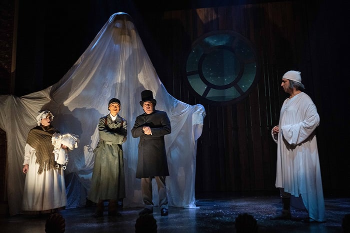 Ghost of Christmas Yet to Come with (l to r) Patty Jamieson as Mrs. Dilber, Jonathan Tan as the Pawnbroker, Jason Cadieux as the Undertaker and Sanjay Talwar as Ebenezer Scrooge (Shaw Festival, 2023). Photo by David Cooper.